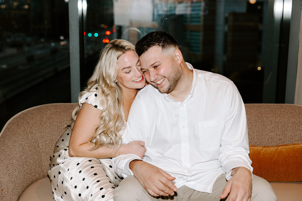 Candid photo of bride and groom sharing a laugh while seated at the rooftop bar.