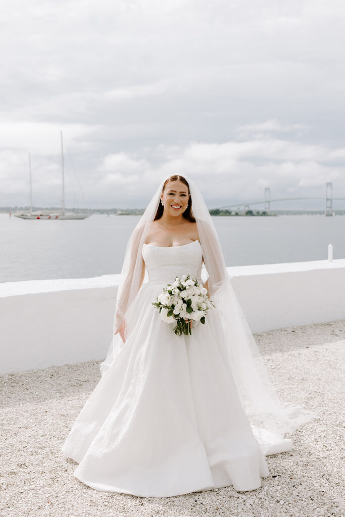 Bride twirling in Anne Barge wedding dress along Newport’s rocky coast
