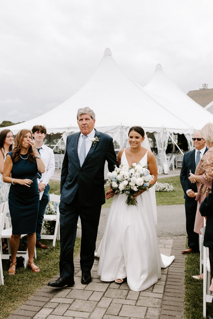 Bride walking down the aisle with a soft ocean breeze in the background