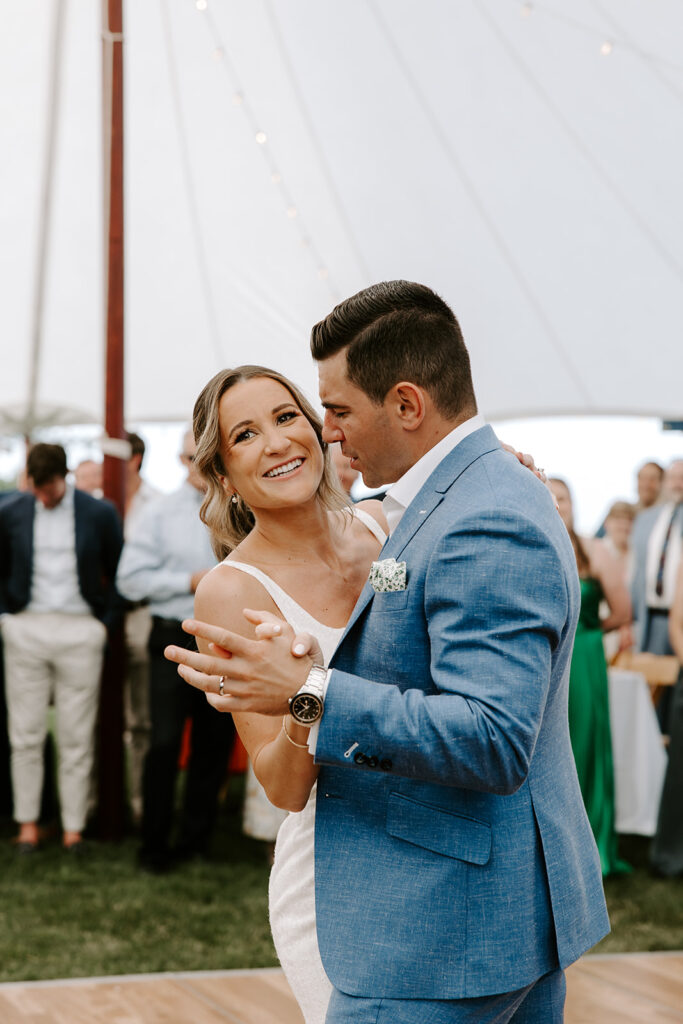 Bride laughing as groom twirls her on the dance floor during their outdoor wedding reception in Orleans, MA