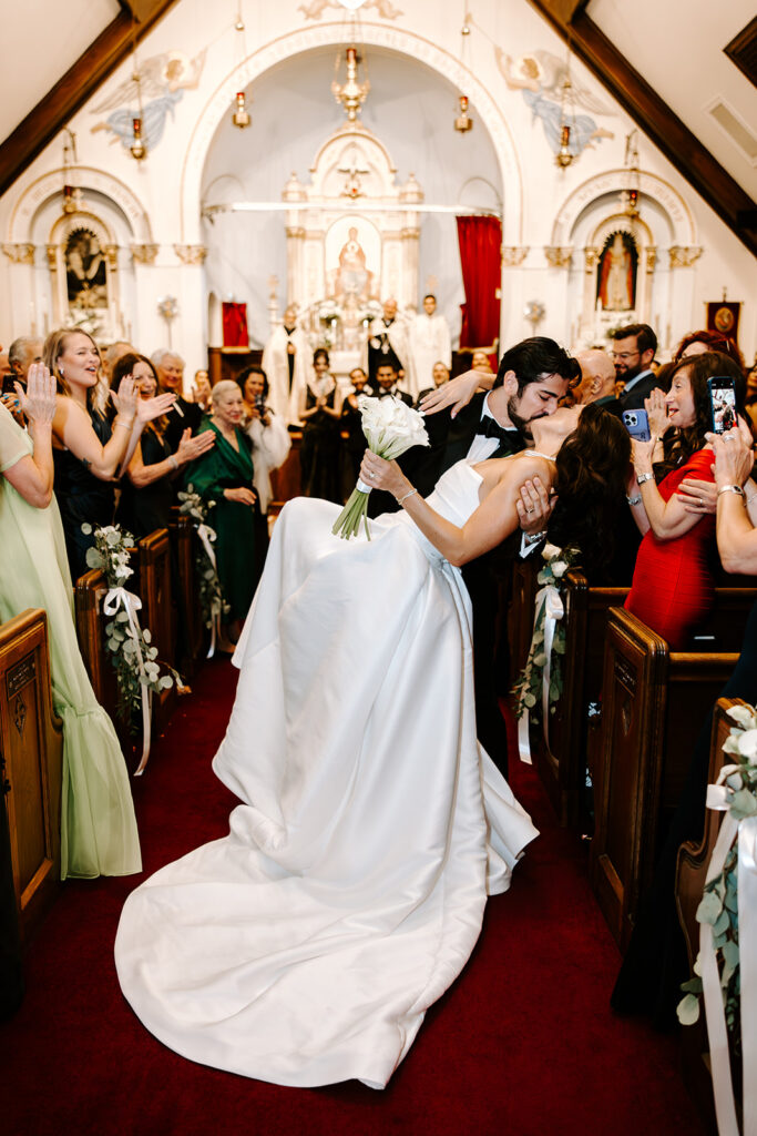 bride and groom first kiss down aisle