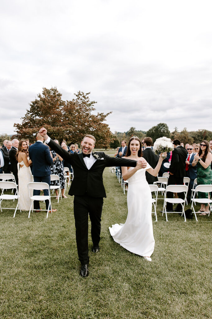 Couple walking back up the aisle hand-in-hand, just married