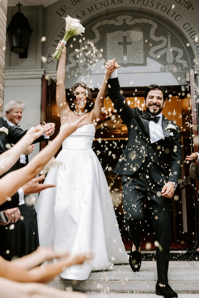 bride and groom exiting church with flower petals