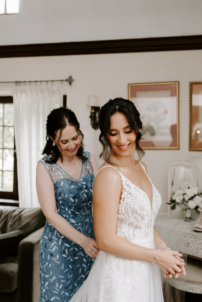 bride's mother helping her button her gown