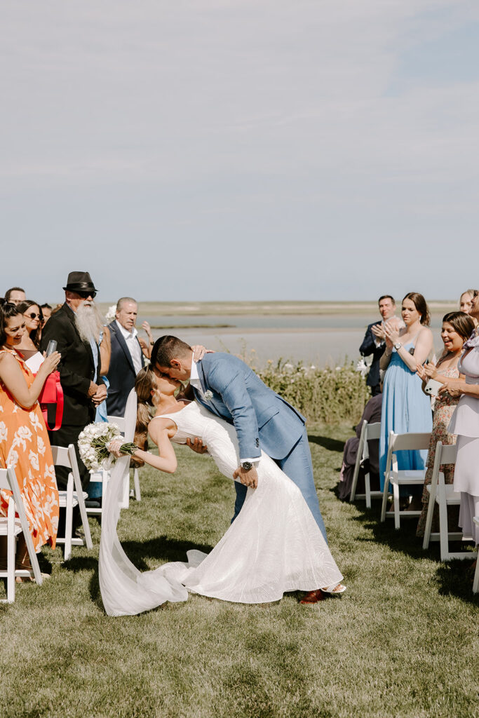 Romantic first kiss as husband and wife in a Cape Cod backyard ceremony.