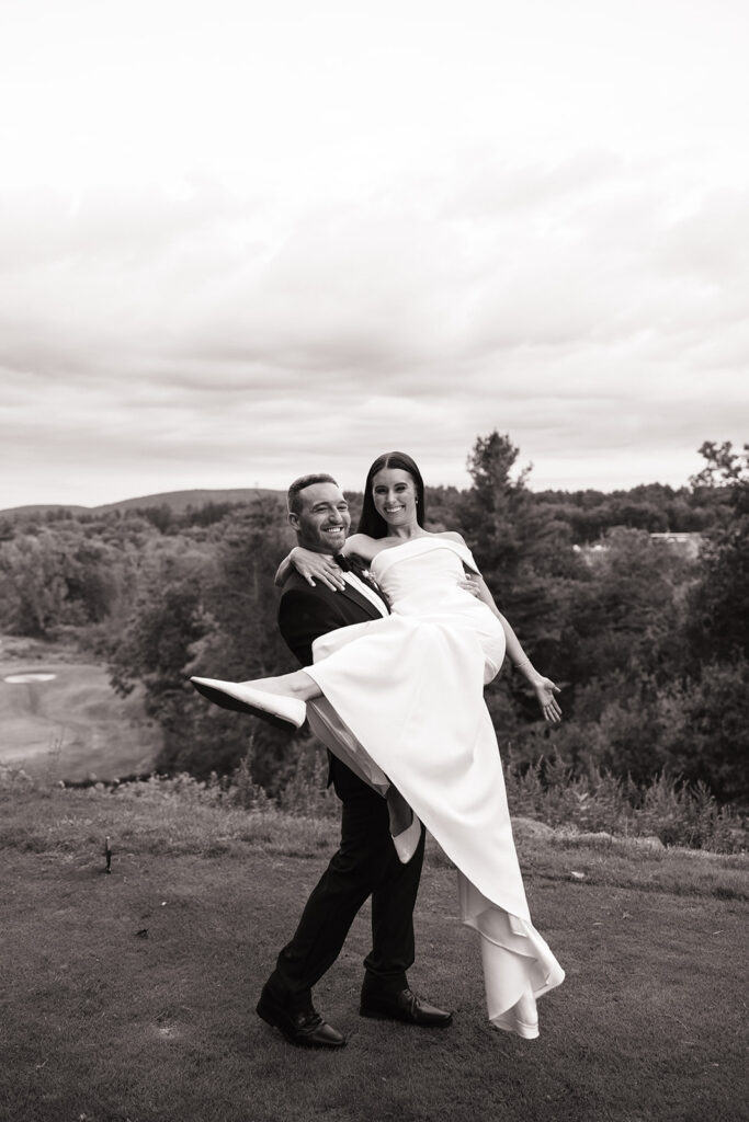 Groom lifting bride as the sun sets behind them