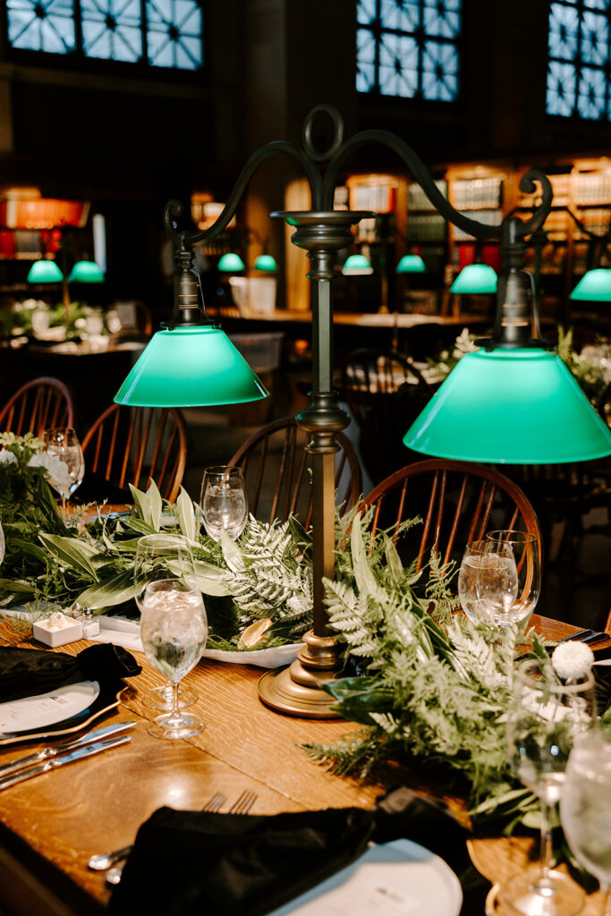 Luxurious black and gold wedding tablescape with candles and green floral accents