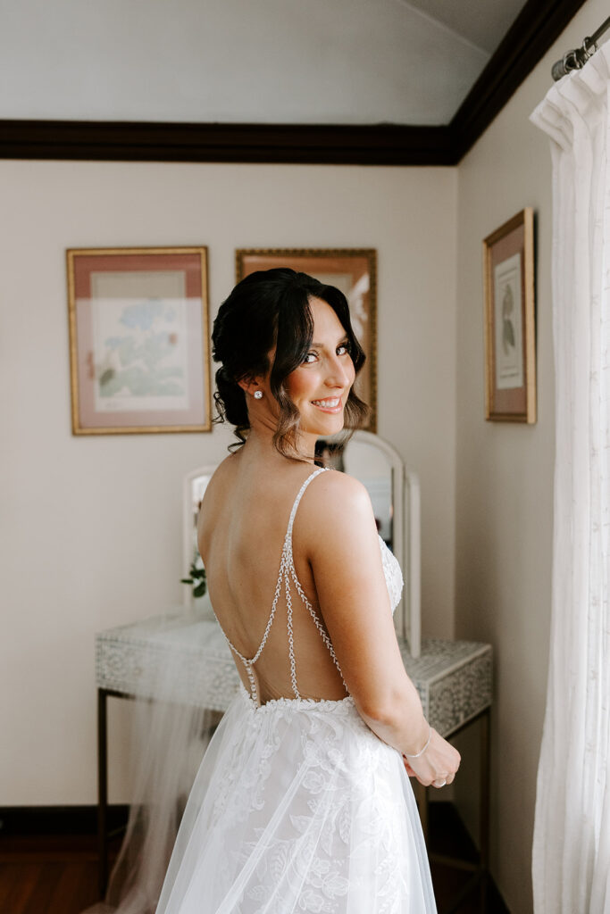 bride looking out the window while getting dressed
