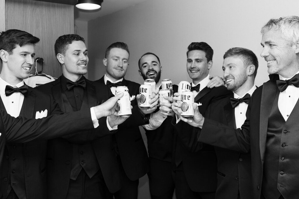 groomsmen cheersing drinks while getting ready
