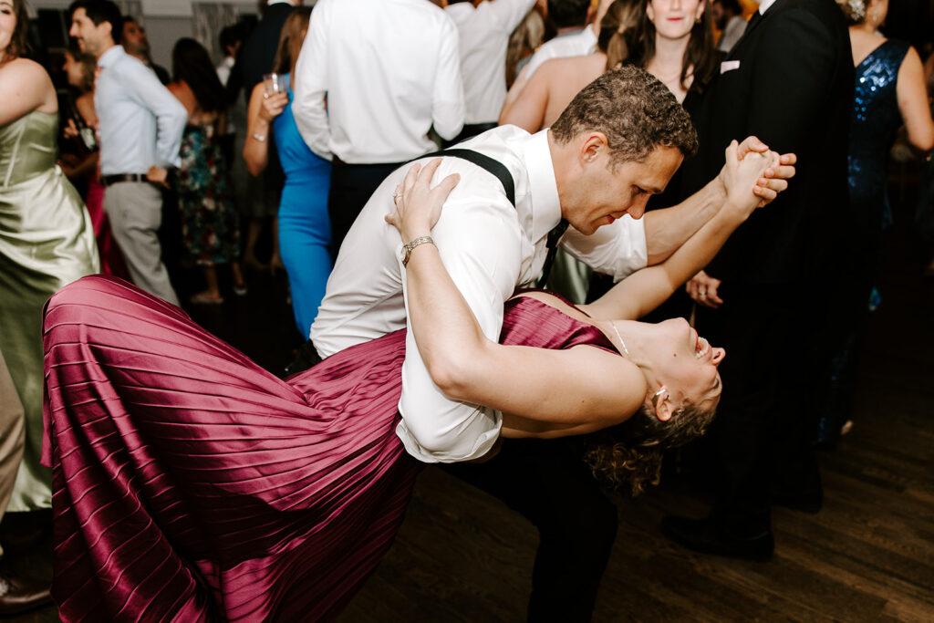 Wedding guests dancing under reception lighting