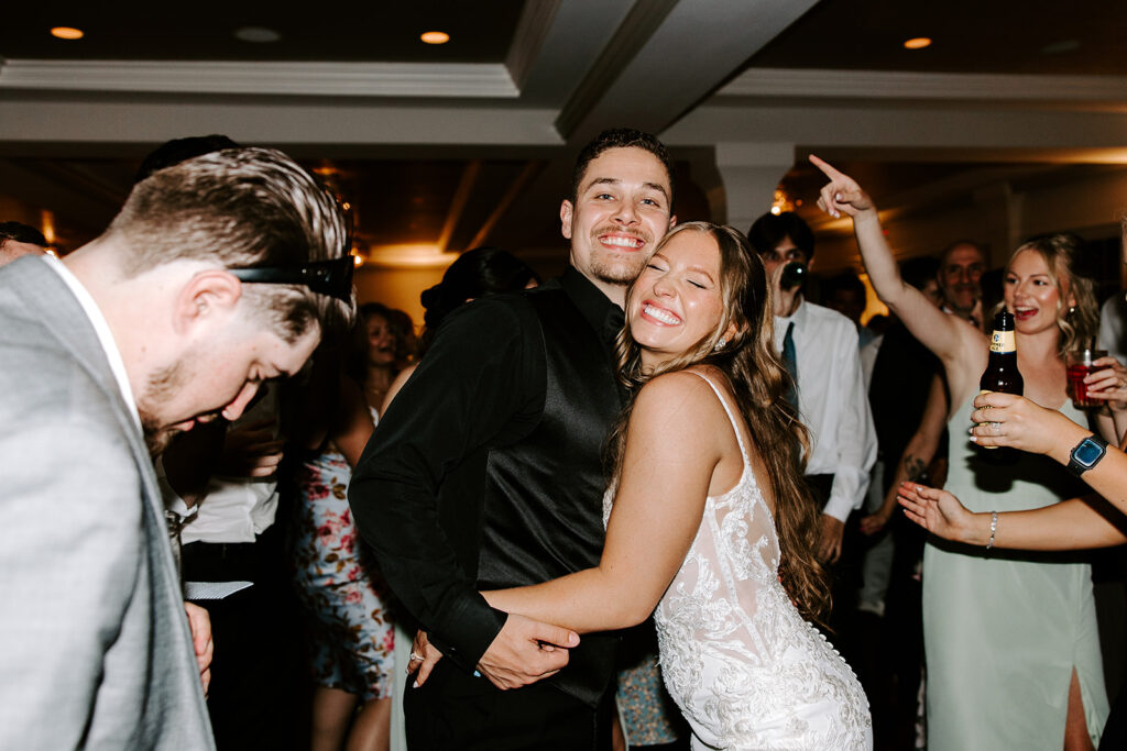 Bride and groom dancing with guests on a packed dance floor