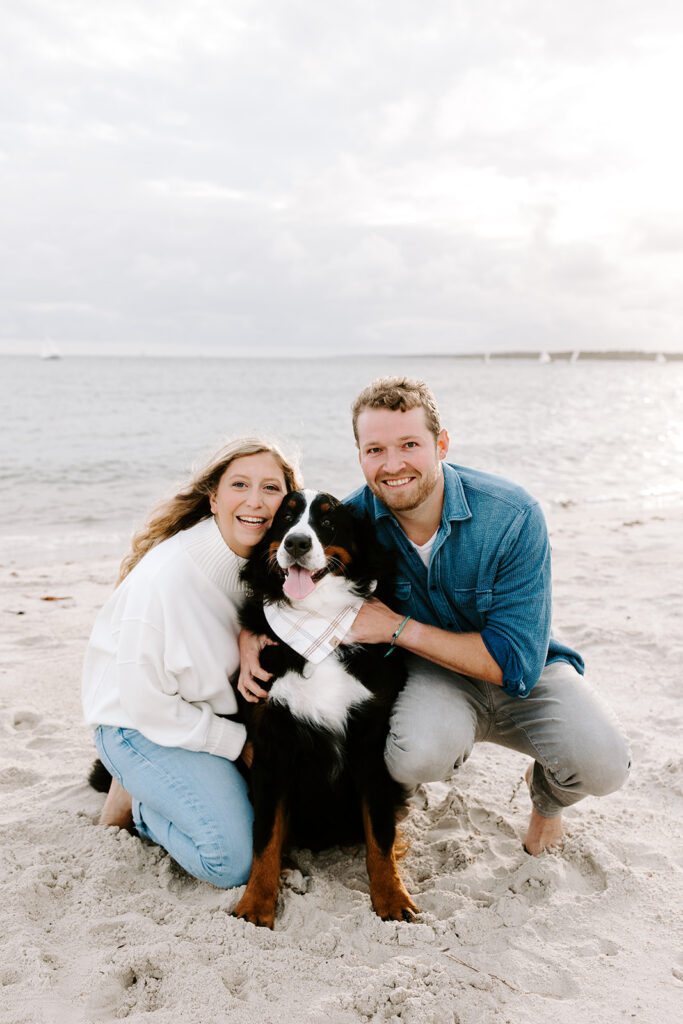 Sweet candid of couple petting their dog by the ocean