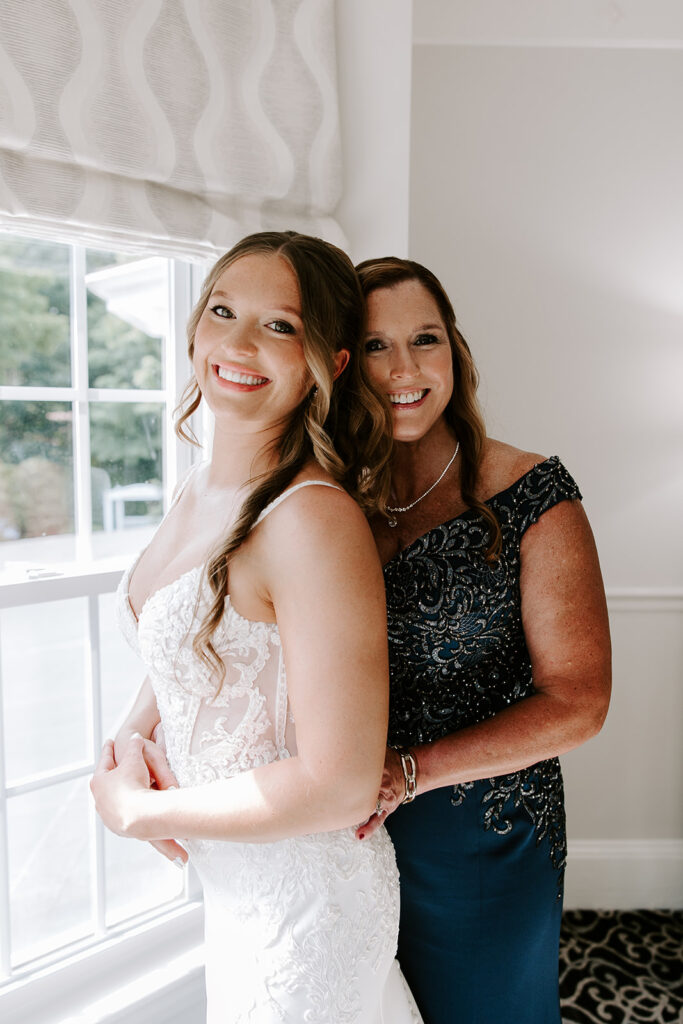 mom helping bride button up dress