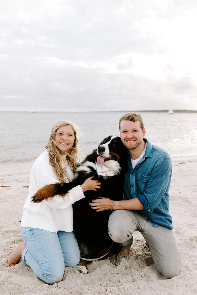 couple hugging their dog on the beach