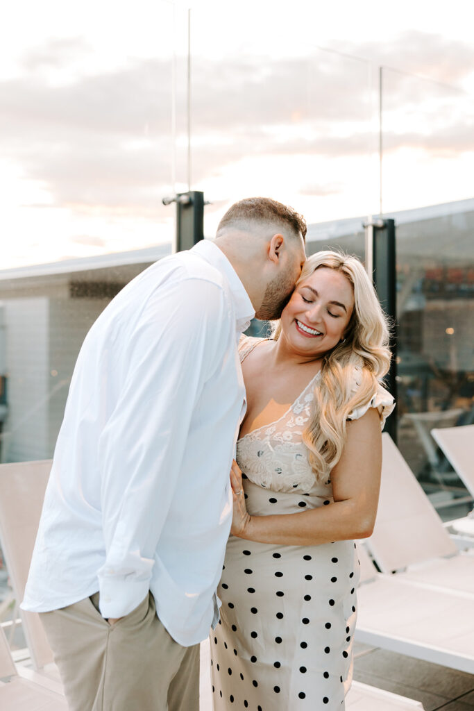 groom kissing bride with sunset behind them