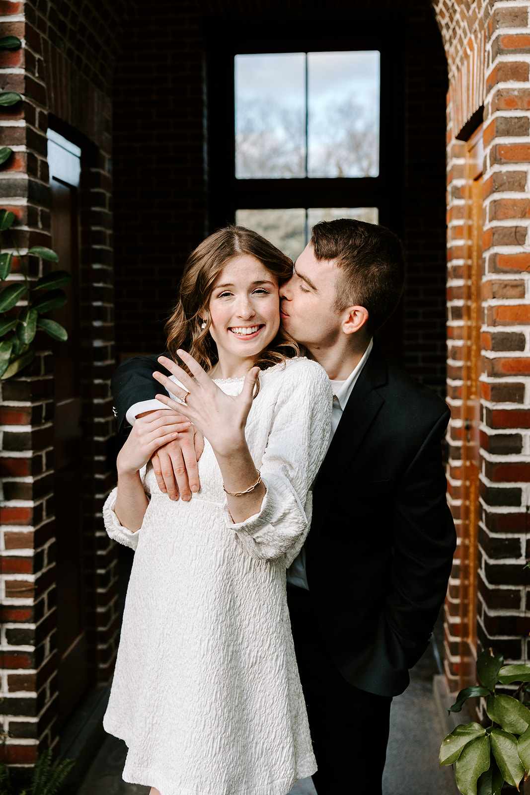 Candid moment of couple laughing inside lush indoor garden space