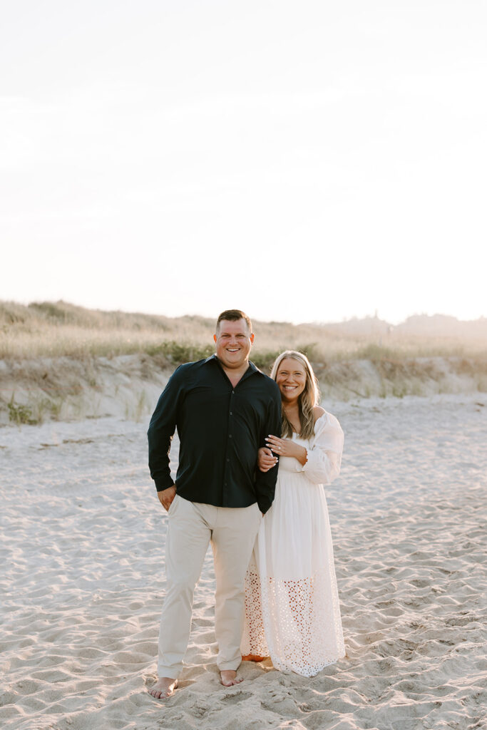 Final portrait of couple standing in soft orange-pink sunset light