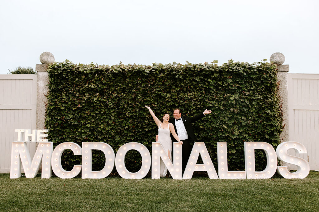 bride and groom posed in front of their sign