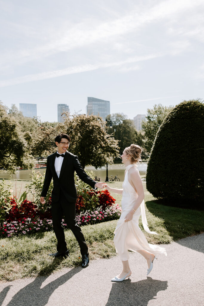 Boston elopement couple laughing in the Public Garden with Boston skyline