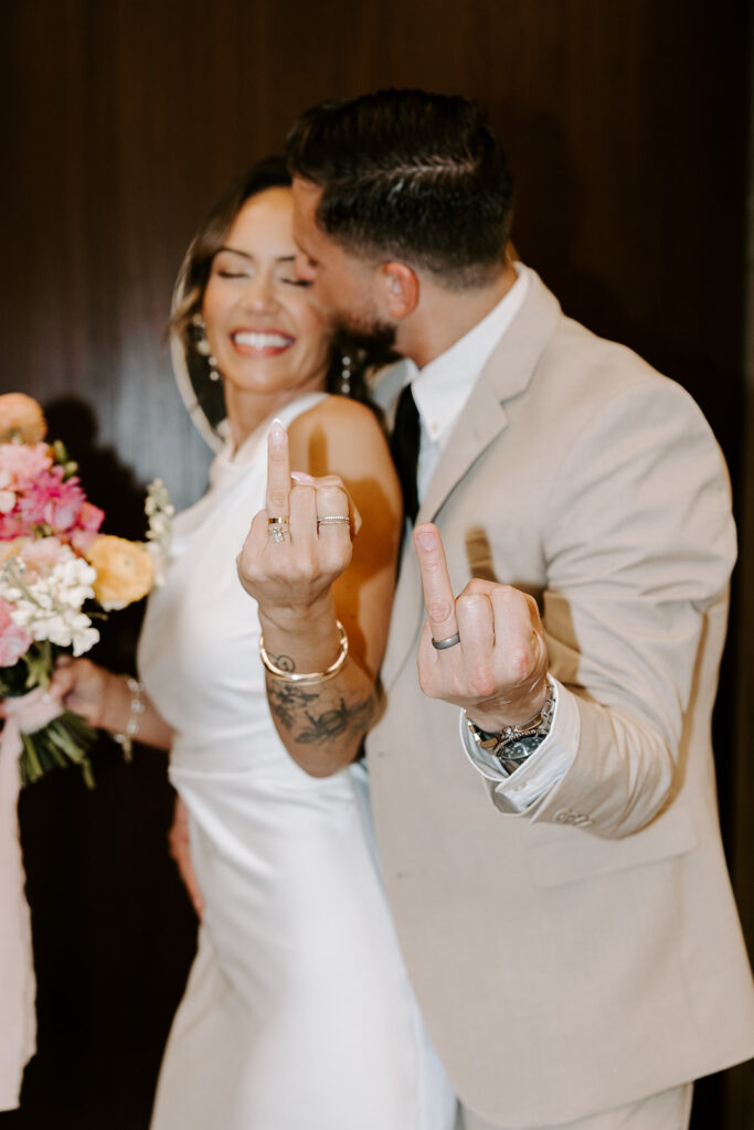 Bride and groom showing off their wedding rings after their Boston City Hall ceremony, bride laughing with eyes closed while groom kisses her cheek, photographed by Genevieve Photography
