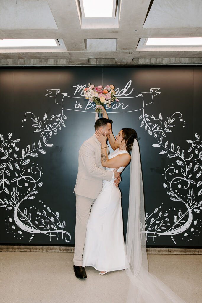 Bride and groom in front of the Married in Boston chalk mural inside Boston City Hall after their wedding ceremony, photographed by Boston wedding photographer Genevieve Photography