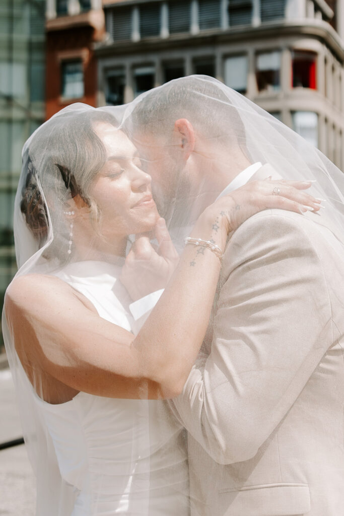 Intimate portrait of bride and groom under the cathedral veil outside Boston City Hall, Boston City Hall wedding photographed by Boston elopement and wedding photographer Genevieve Photography
